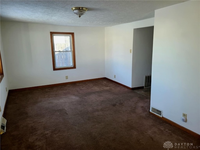 carpeted spare room featuring visible vents, a textured ceiling, and baseboards