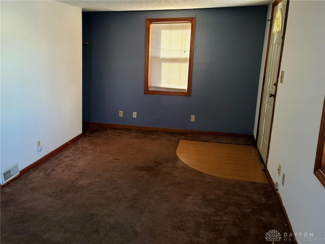 unfurnished room featuring dark carpet