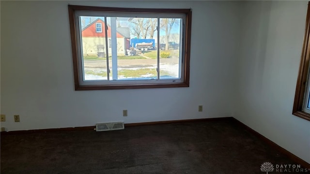 unfurnished room featuring baseboards, visible vents, and dark colored carpet