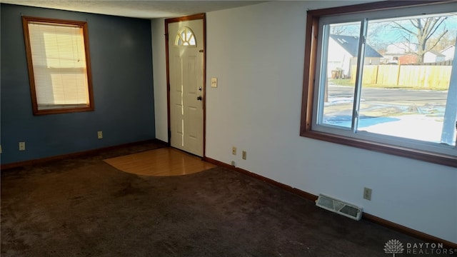 empty room with baseboards, visible vents, and carpet flooring