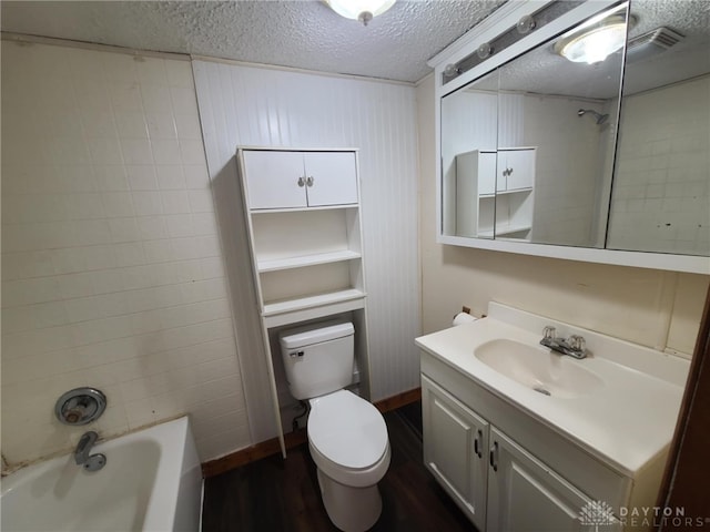 full bathroom featuring tiled shower / bath combo, vanity, wood-type flooring, a textured ceiling, and toilet