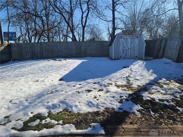 yard layered in snow featuring a storage shed