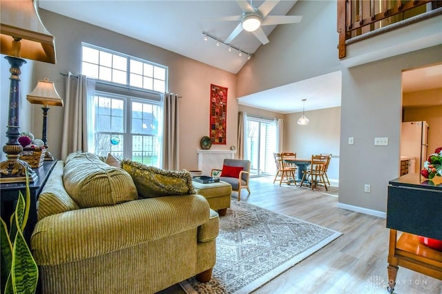 living room with high vaulted ceiling, track lighting, light hardwood / wood-style floors, and ceiling fan