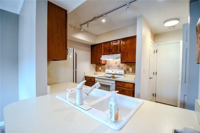 kitchen featuring tasteful backsplash, sink, white appliances, and kitchen peninsula