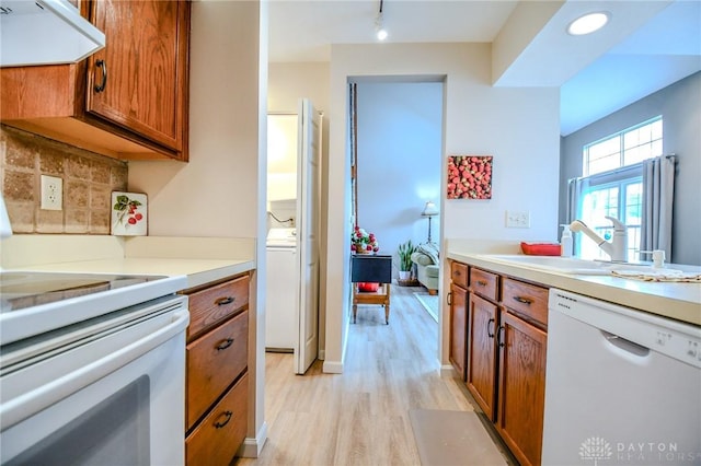 kitchen featuring range hood, sink, decorative backsplash, light hardwood / wood-style floors, and white appliances