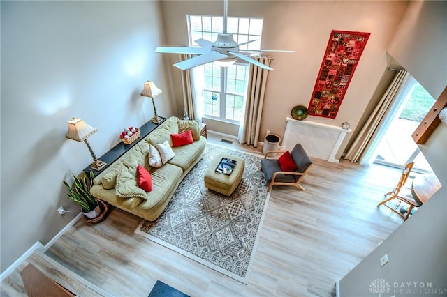 living room with hardwood / wood-style flooring, ceiling fan, and a high ceiling