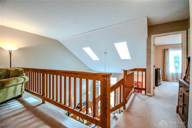 hall with lofted ceiling with skylight and light colored carpet