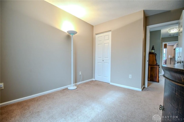 unfurnished bedroom featuring light carpet and a closet