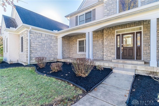 doorway to property with covered porch and a lawn