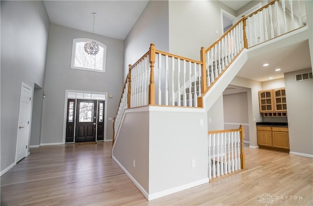 entryway with hardwood / wood-style flooring, a towering ceiling, and a notable chandelier