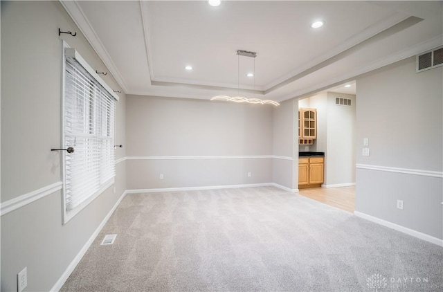 carpeted spare room with a tray ceiling and ornamental molding