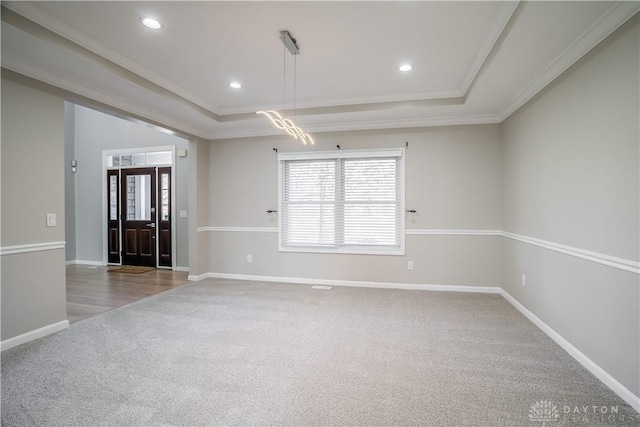 foyer entrance featuring a tray ceiling, ornamental molding, and carpet flooring