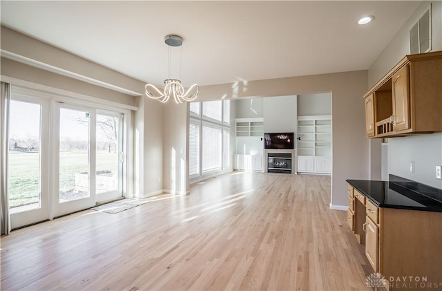 kitchen featuring built in features, a chandelier, light hardwood / wood-style floors, and hanging light fixtures