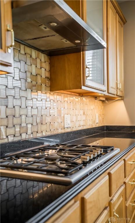 kitchen with stainless steel gas stovetop, extractor fan, and decorative backsplash