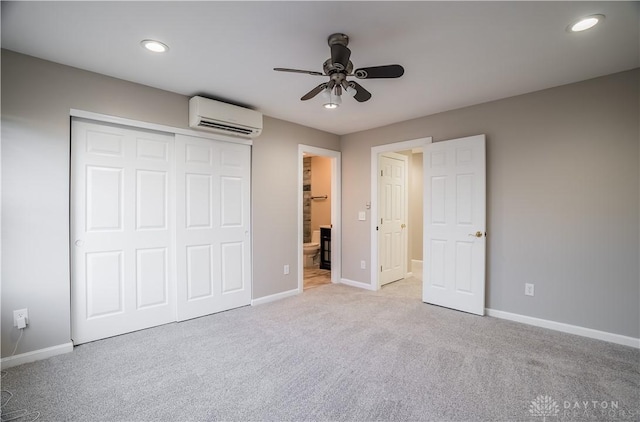 unfurnished bedroom featuring an AC wall unit, connected bathroom, ceiling fan, light carpet, and a closet