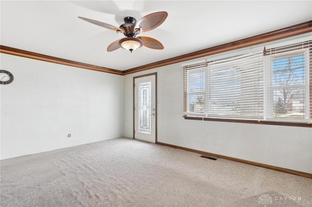 carpeted empty room with crown molding, ceiling fan, and a wealth of natural light