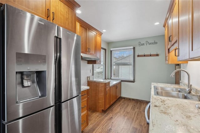 kitchen featuring sink, stainless steel dishwasher, ceiling fan, light stone counters, and light wood-type flooring