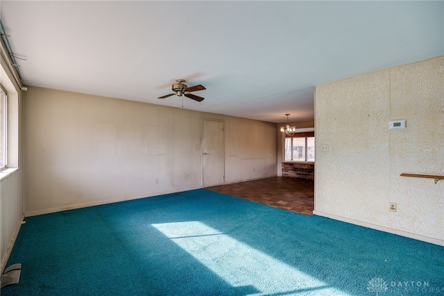 carpeted spare room featuring ceiling fan with notable chandelier