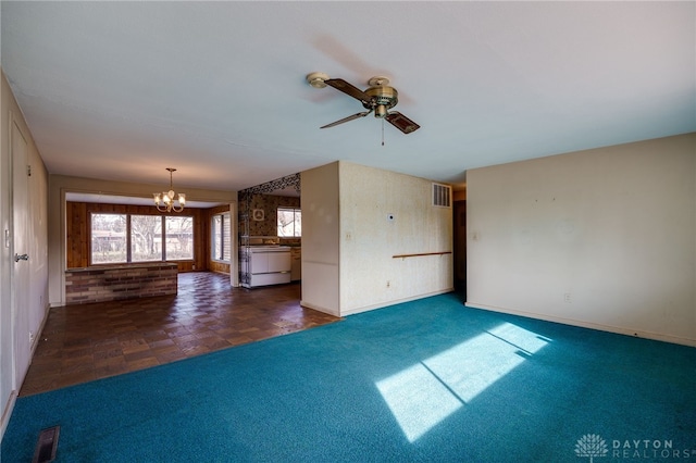 unfurnished living room featuring ceiling fan with notable chandelier and dark carpet