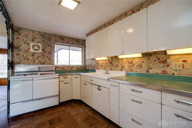 kitchen with white cabinetry, dark parquet floors, sink, and range with two ovens