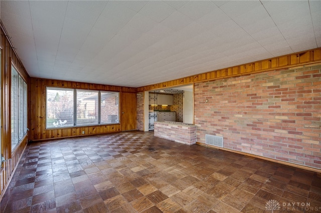 unfurnished living room with brick wall