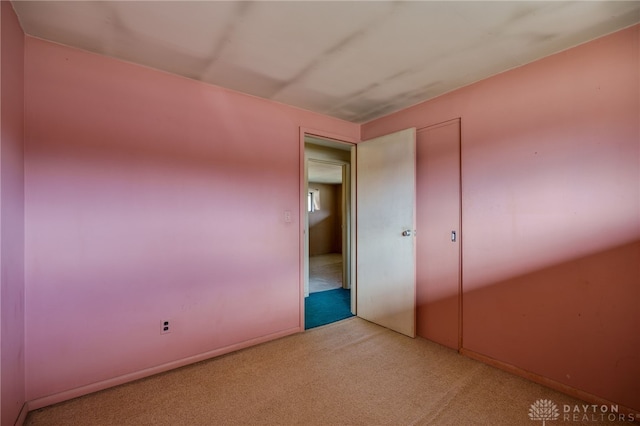 unfurnished bedroom with light colored carpet and a closet