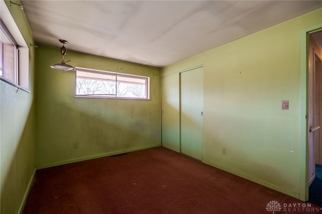 unfurnished bedroom with a closet and dark colored carpet