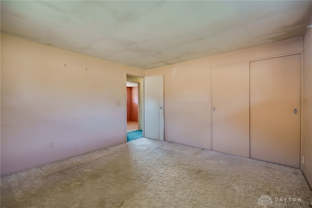 unfurnished bedroom with light colored carpet and a closet