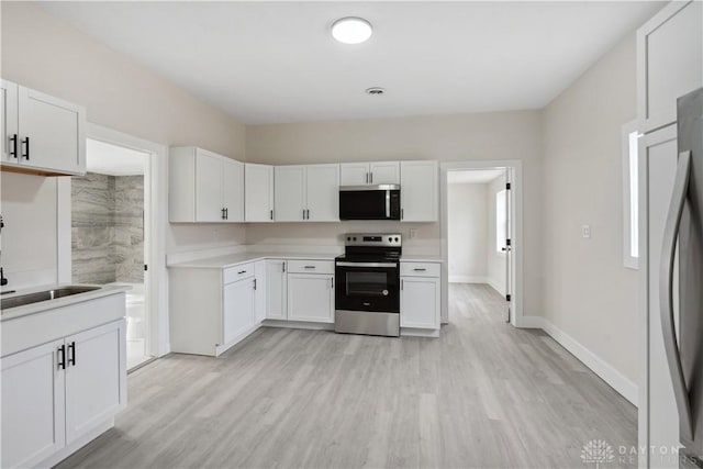 kitchen featuring stainless steel appliances, white cabinets, and light hardwood / wood-style floors