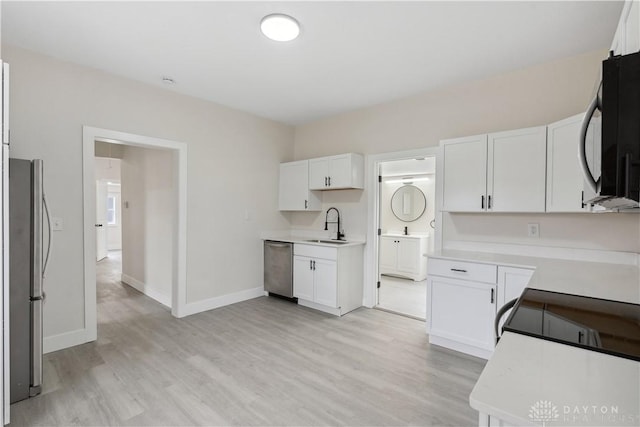 kitchen featuring white cabinetry, sink, stainless steel appliances, and light wood-type flooring