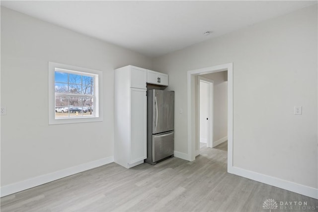 unfurnished bedroom featuring stainless steel fridge and light hardwood / wood-style floors