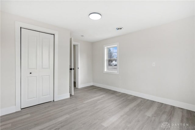 unfurnished bedroom with a closet and light wood-type flooring