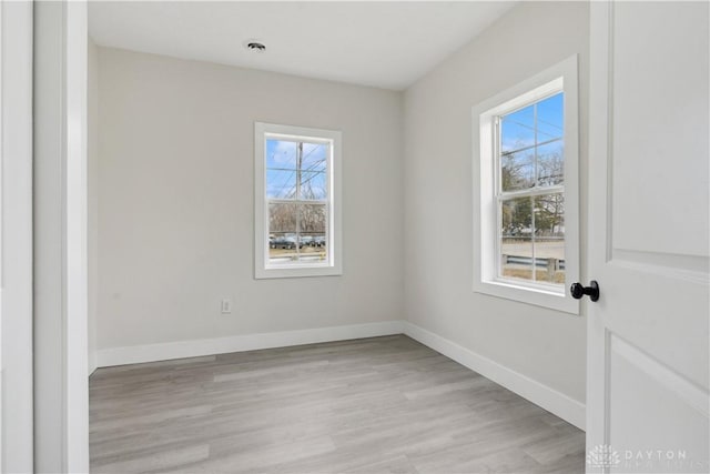 empty room with light hardwood / wood-style flooring and plenty of natural light