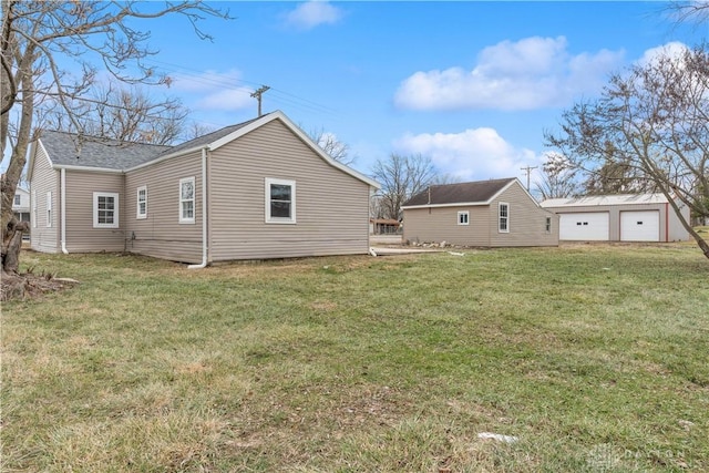 rear view of property featuring an outbuilding, a garage, and a lawn