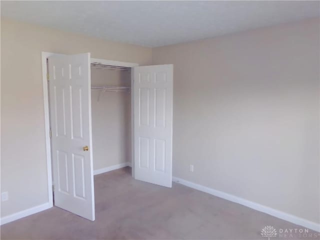 unfurnished bedroom with light carpet and a closet