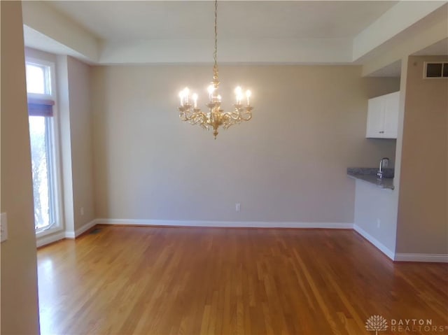 unfurnished dining area with an inviting chandelier and hardwood / wood-style floors