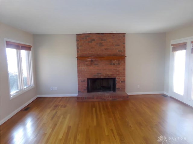 unfurnished living room featuring a brick fireplace and light hardwood / wood-style floors