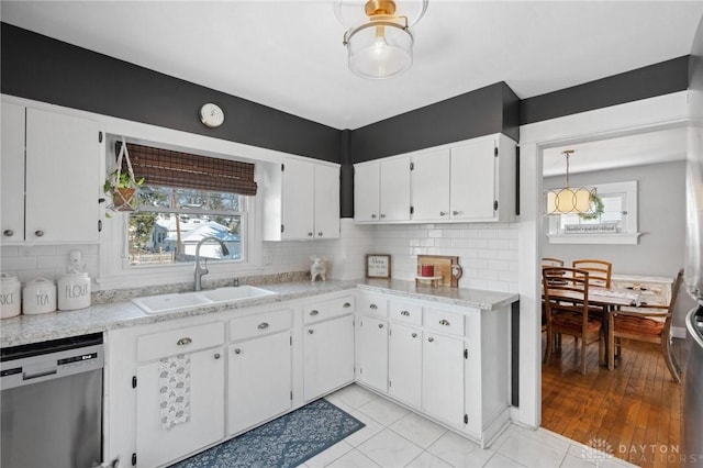 kitchen featuring sink, hanging light fixtures, plenty of natural light, white cabinets, and stainless steel dishwasher