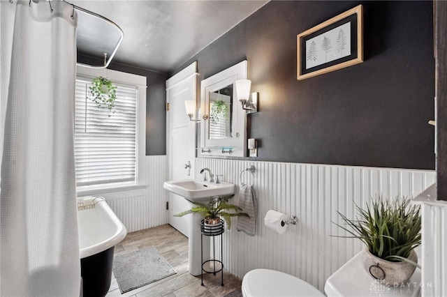 bathroom with a bathing tub, sink, hardwood / wood-style floors, and toilet