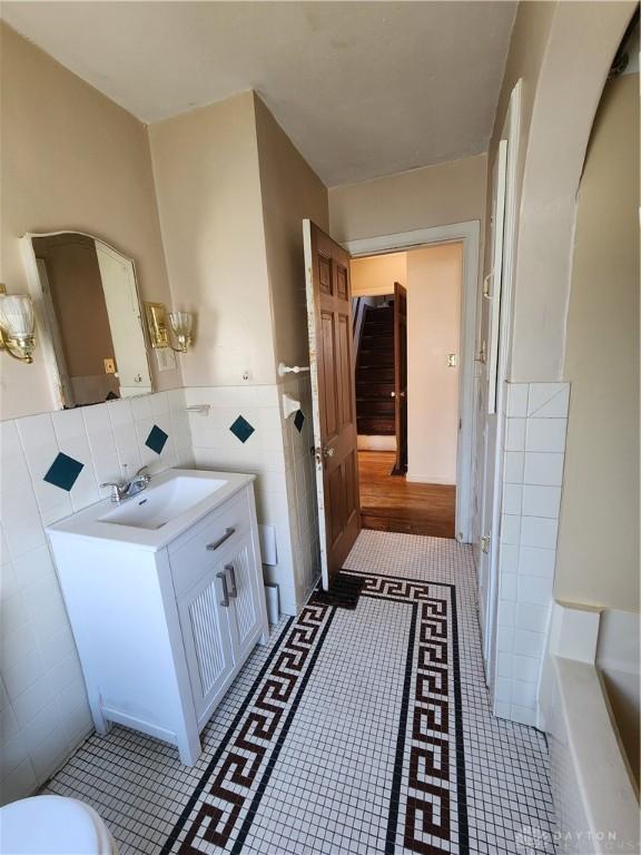 bathroom with tile patterned flooring, vanity, and tile walls