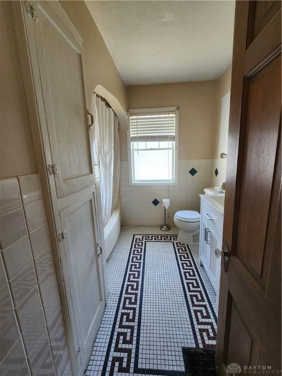 full bathroom featuring tile patterned floors, toilet, tile walls, vanity, and shower / bath combo