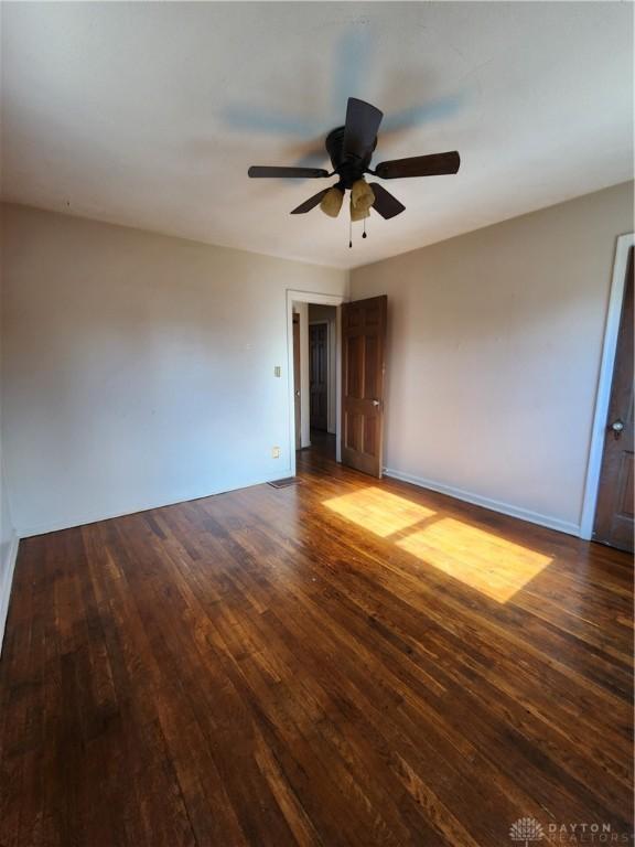 unfurnished room with dark wood-type flooring and ceiling fan