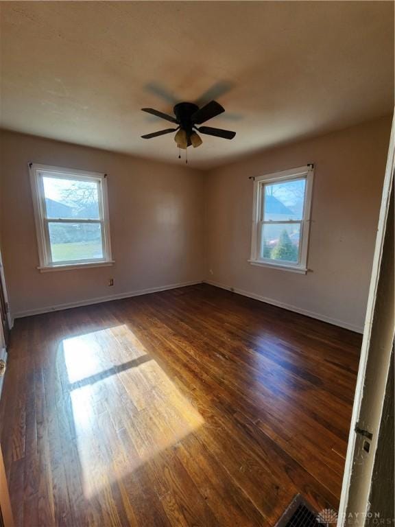 spare room featuring ceiling fan, a wealth of natural light, and dark hardwood / wood-style flooring