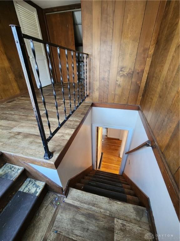 stairway with hardwood / wood-style flooring and wood walls