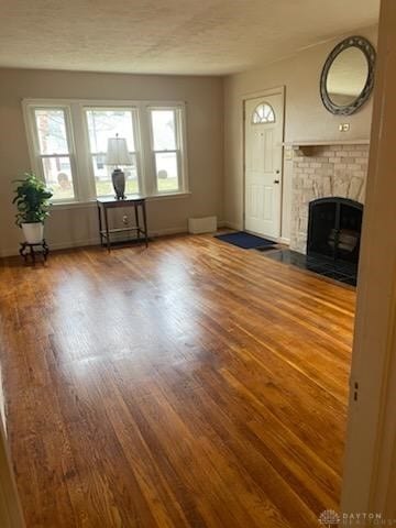 unfurnished living room featuring dark wood-type flooring, a fireplace, and a wealth of natural light