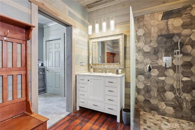 bathroom with hardwood / wood-style flooring, vanity, and a tile shower