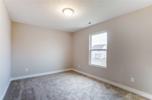 carpeted empty room with a healthy amount of sunlight and a textured ceiling