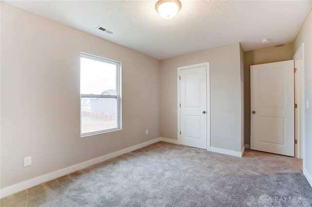 unfurnished bedroom with light carpet and a textured ceiling