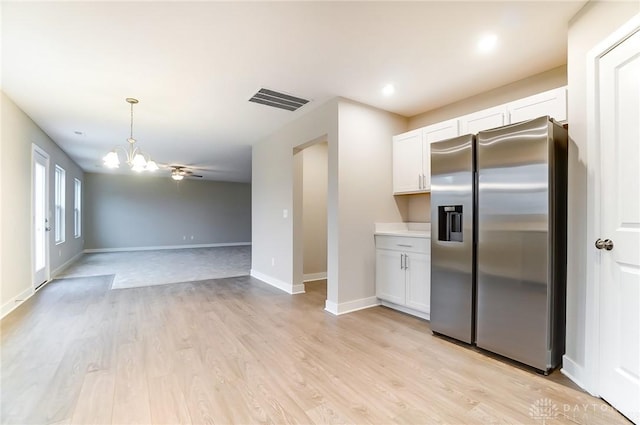 kitchen featuring light hardwood / wood-style flooring, stainless steel fridge, hanging light fixtures, a notable chandelier, and white cabinets