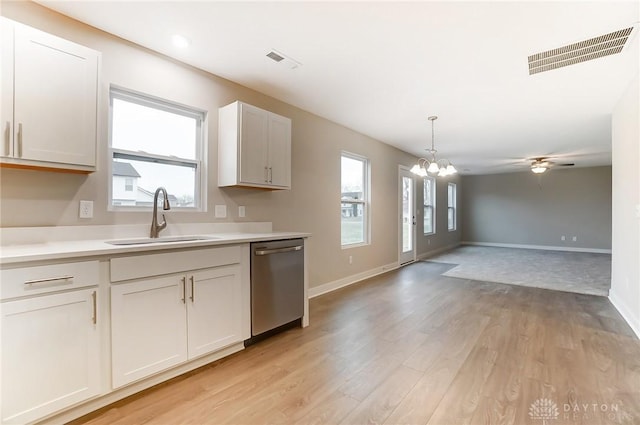 kitchen with sink, hanging light fixtures, light wood-type flooring, stainless steel dishwasher, and white cabinets